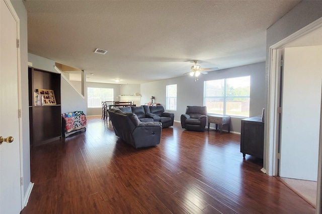 living area featuring baseboards, visible vents, dark wood-style floors, ceiling fan, and a textured ceiling