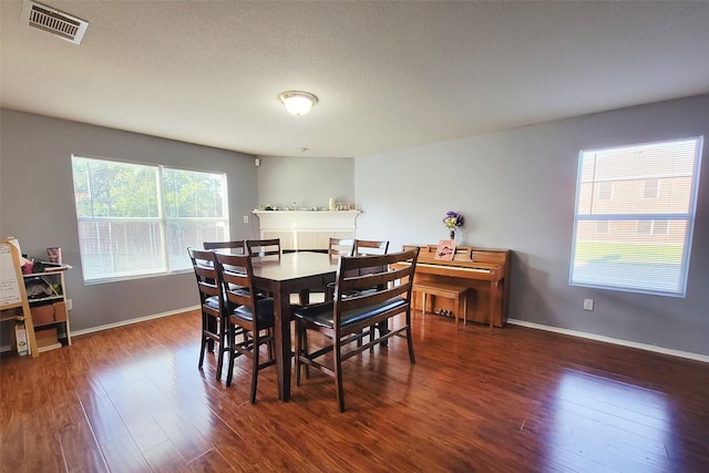 dining space with dark wood-style floors, visible vents, and baseboards