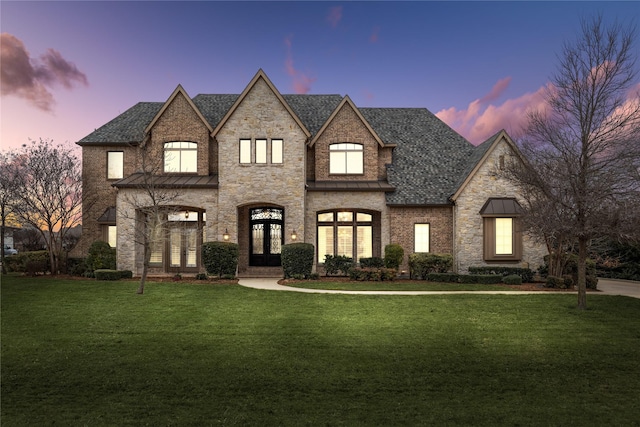 view of front of home featuring french doors, a front yard, brick siding, and a shingled roof