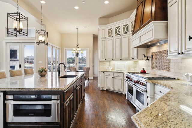 kitchen featuring appliances with stainless steel finishes, an island with sink, a sink, and light stone countertops