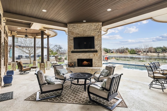 view of patio / terrace with ceiling fan, an outdoor stone fireplace, fence, and a fenced in pool