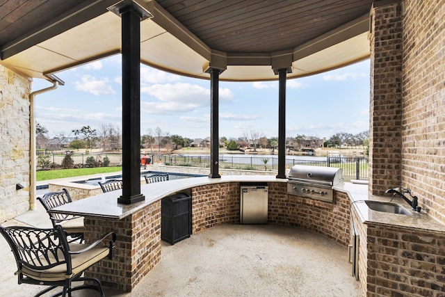 view of patio / terrace with an outdoor kitchen, outdoor wet bar, a sink, fence, and grilling area