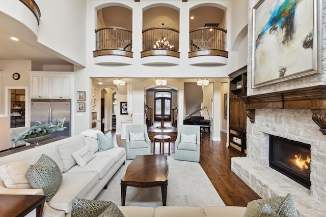 living area featuring baseboards, arched walkways, a towering ceiling, dark wood-type flooring, and a fireplace