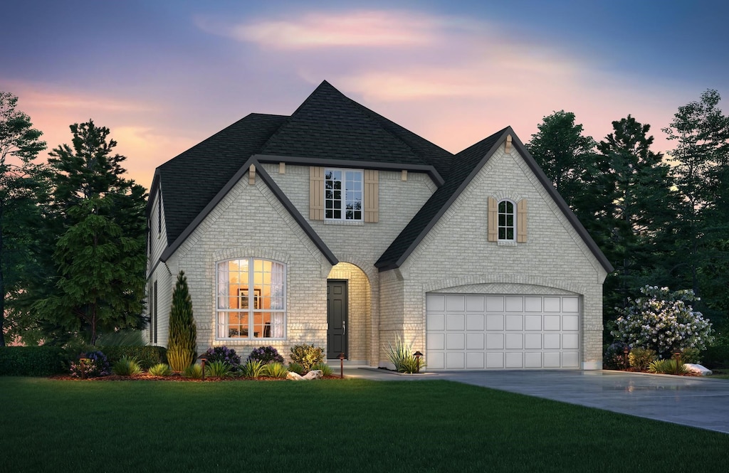 french provincial home featuring driveway, a yard, and brick siding