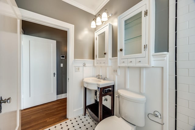 bathroom featuring a sink, wood finished floors, toilet, and crown molding