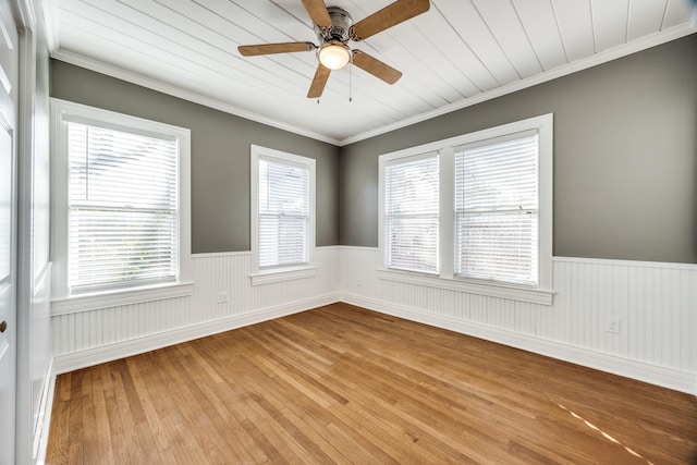 unfurnished room featuring crown molding, wainscoting, and light wood-style floors