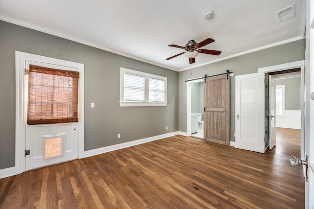 unfurnished bedroom with a barn door, visible vents, baseboards, dark wood-style floors, and crown molding