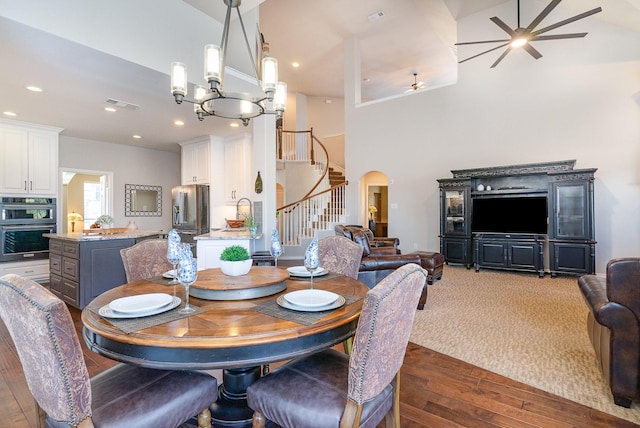 dining room featuring arched walkways, dark wood-style flooring, a towering ceiling, visible vents, and stairway