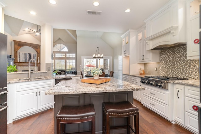 kitchen featuring visible vents, glass insert cabinets, premium range hood, stainless steel gas stovetop, and a sink