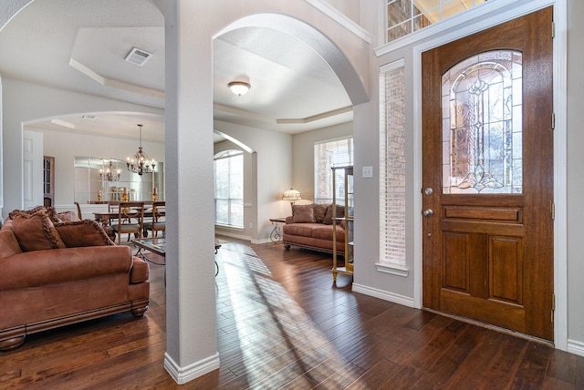 entryway featuring dark wood-style flooring, a raised ceiling, visible vents, a chandelier, and baseboards