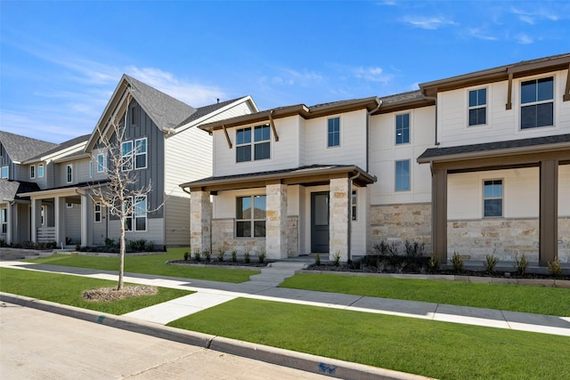 multi unit property with stone siding, a residential view, and a front lawn