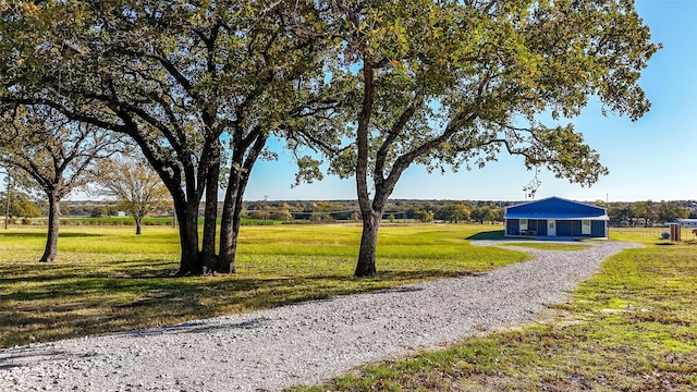 surrounding community with gravel driveway and a yard