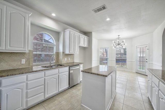 kitchen featuring a sink, visible vents, white cabinetry, stainless steel dishwasher, and dark stone countertops