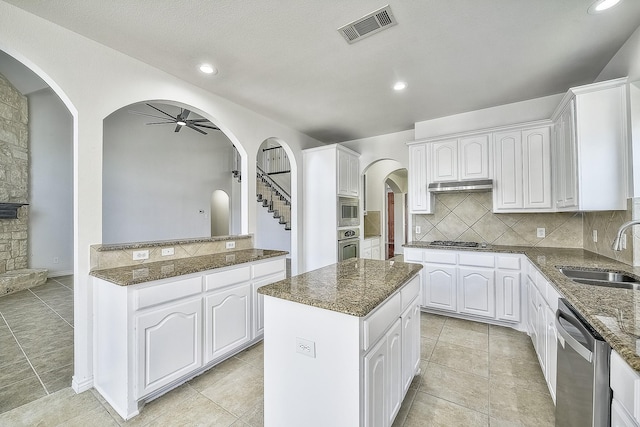 kitchen with stainless steel appliances, visible vents, white cabinets, a kitchen island, and a sink