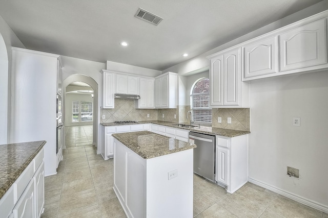 kitchen with stainless steel appliances, visible vents, white cabinets, a kitchen island, and a sink