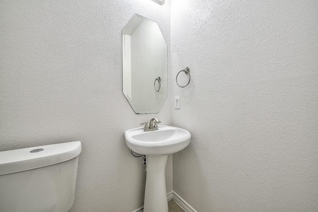 bathroom with a sink, a textured wall, and toilet