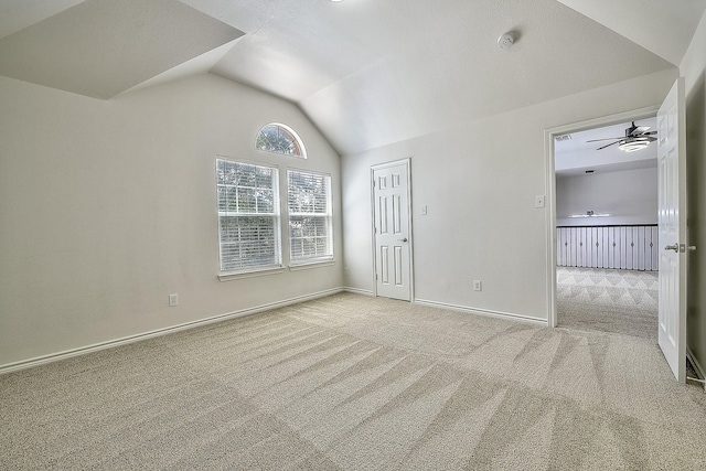 empty room featuring lofted ceiling, light carpet, a ceiling fan, and baseboards