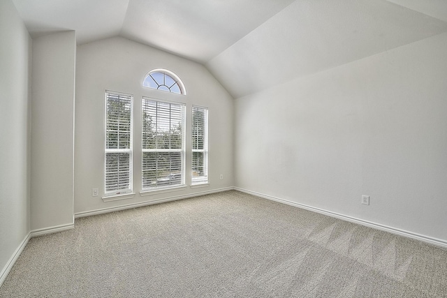 spare room with carpet flooring, vaulted ceiling, and baseboards