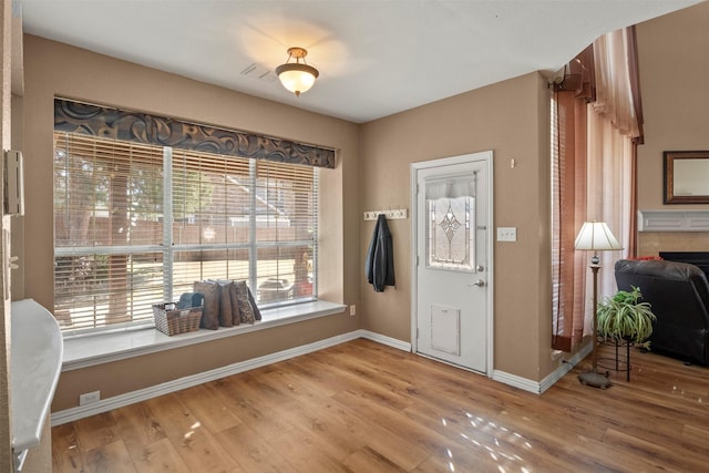 foyer with visible vents, a fireplace, baseboards, and wood finished floors