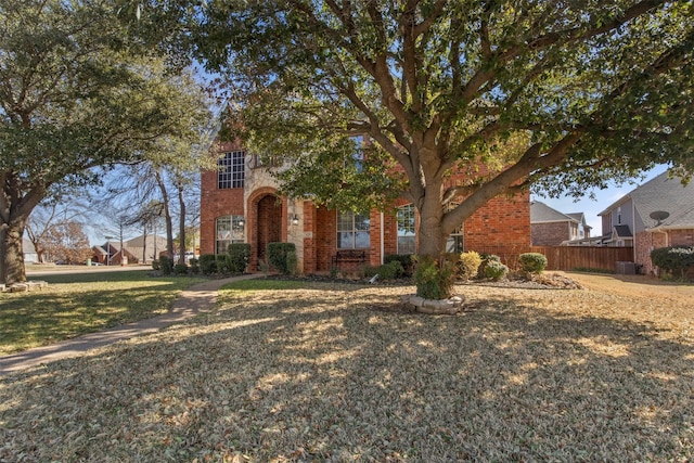 obstructed view of property featuring fence, a front lawn, and brick siding