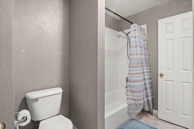 full bathroom with a textured wall, shower / tub combo with curtain, and toilet