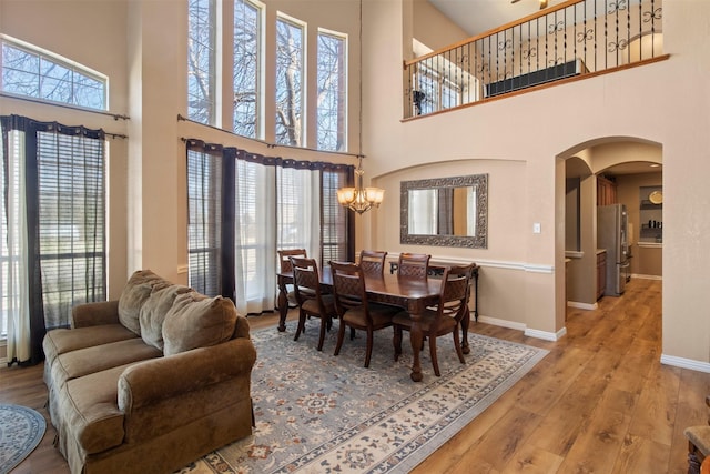 dining area featuring a chandelier, arched walkways, baseboards, and wood finished floors