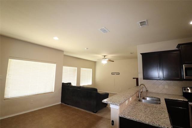 kitchen with range with electric cooktop, visible vents, decorative backsplash, stainless steel microwave, and a sink