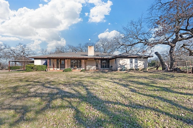 rear view of house featuring a lawn and a chimney