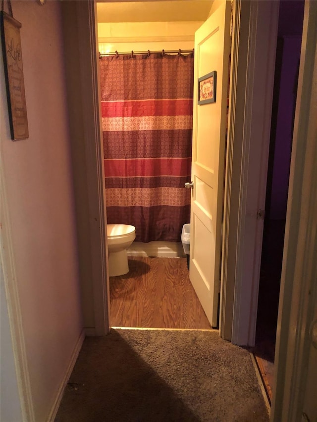 full bathroom featuring curtained shower, toilet, and baseboards