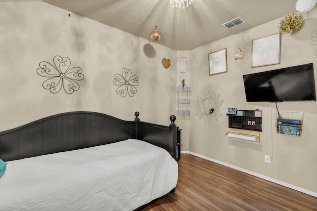 bedroom featuring wood finished floors, visible vents, and baseboards