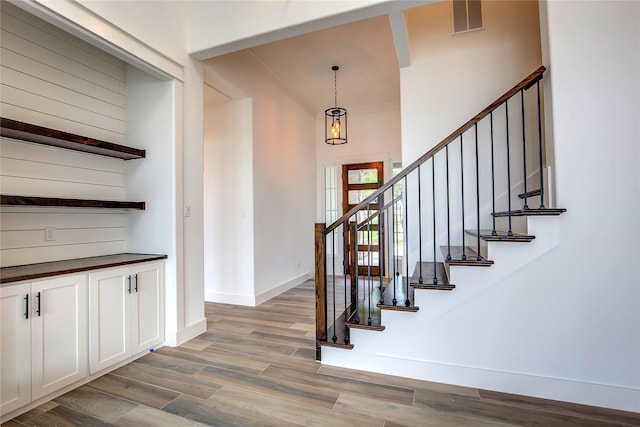 stairway with visible vents, crown molding, baseboards, and wood finished floors