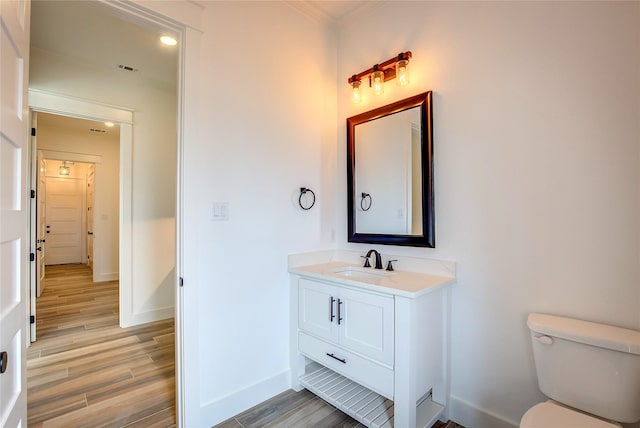 bathroom featuring toilet, wood finished floors, visible vents, vanity, and baseboards