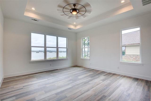 spare room with a water view, visible vents, and a raised ceiling