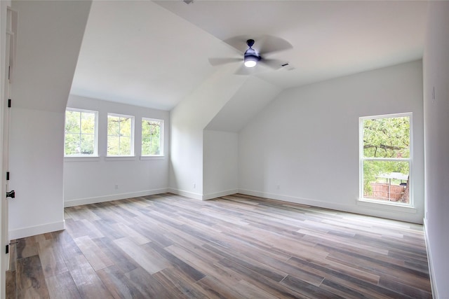 additional living space featuring light wood-style floors, baseboards, vaulted ceiling, and a wealth of natural light