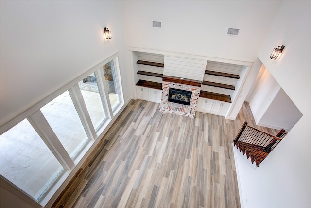 living area with a high ceiling, visible vents, a fireplace, and wood finished floors