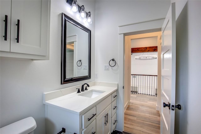 half bath with toilet, wood finished floors, and vanity