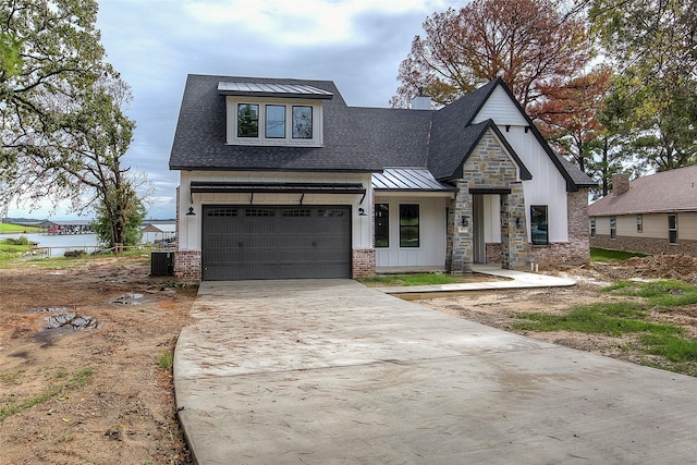 modern inspired farmhouse featuring metal roof, a shingled roof, a water view, driveway, and a standing seam roof