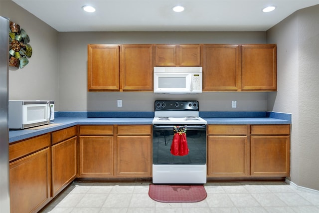 kitchen featuring white microwave, electric range, brown cabinetry, and recessed lighting