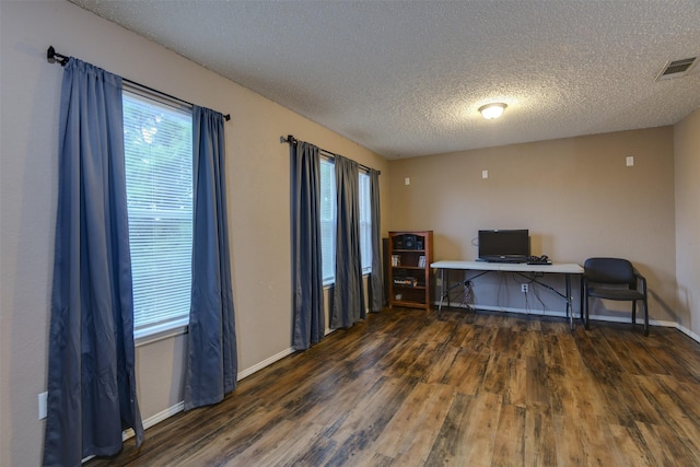 office area with baseboards, visible vents, dark wood finished floors, and a textured ceiling