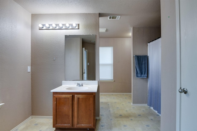 bathroom featuring visible vents, a textured wall, vanity, and tile patterned floors