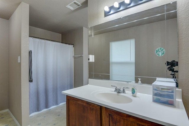 full bath with a textured wall, visible vents, and vanity