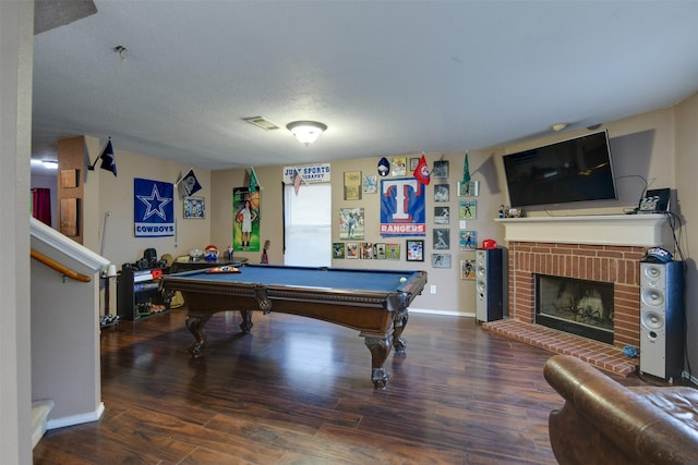 rec room featuring a textured ceiling, billiards, wood finished floors, baseboards, and a brick fireplace