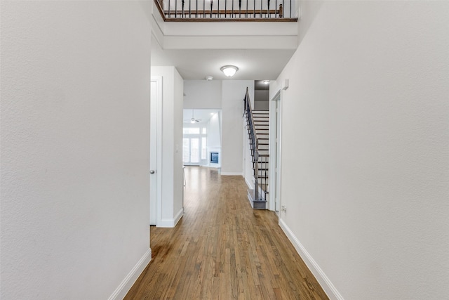 hall with baseboards, a high ceiling, stairway, and wood finished floors