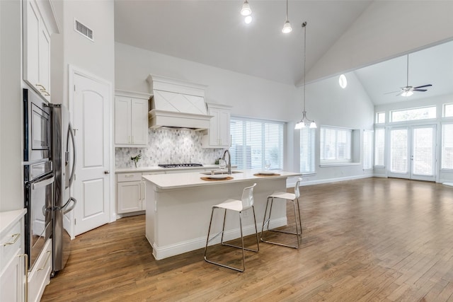 kitchen featuring light countertops, custom range hood, stainless steel oven, and gas cooktop