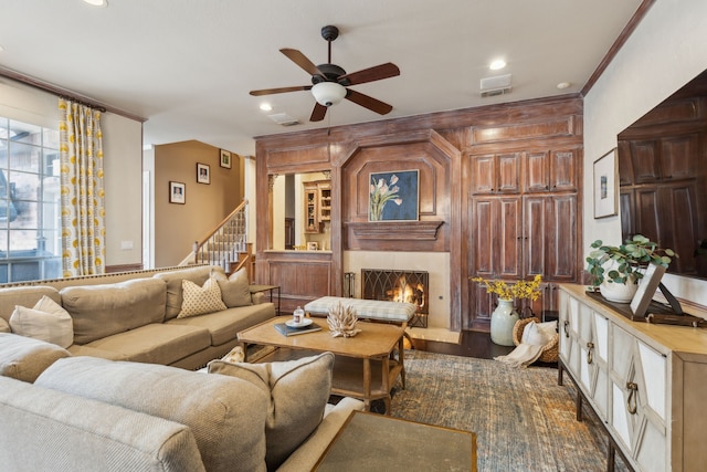 living room featuring a lit fireplace, stairway, crown molding, and recessed lighting