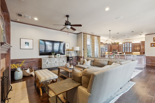 living area with crown molding, a fireplace, recessed lighting, wainscoting, and wood finished floors