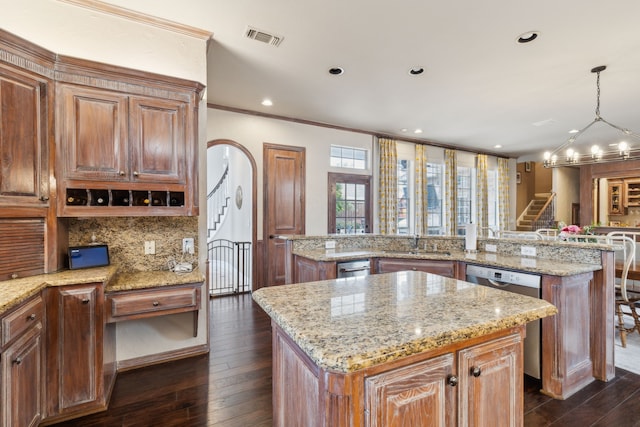 kitchen featuring visible vents, hanging light fixtures, stainless steel dishwasher, a kitchen island, and a peninsula