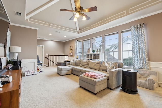 carpeted living area featuring a ceiling fan, a decorative wall, visible vents, and crown molding