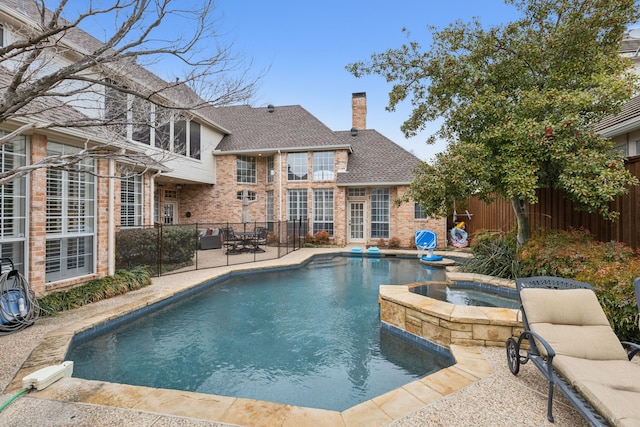 view of swimming pool with a pool with connected hot tub, fence, and a patio