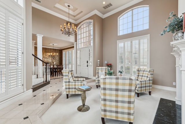 foyer with a notable chandelier, decorative columns, visible vents, ornamental molding, and a healthy amount of sunlight